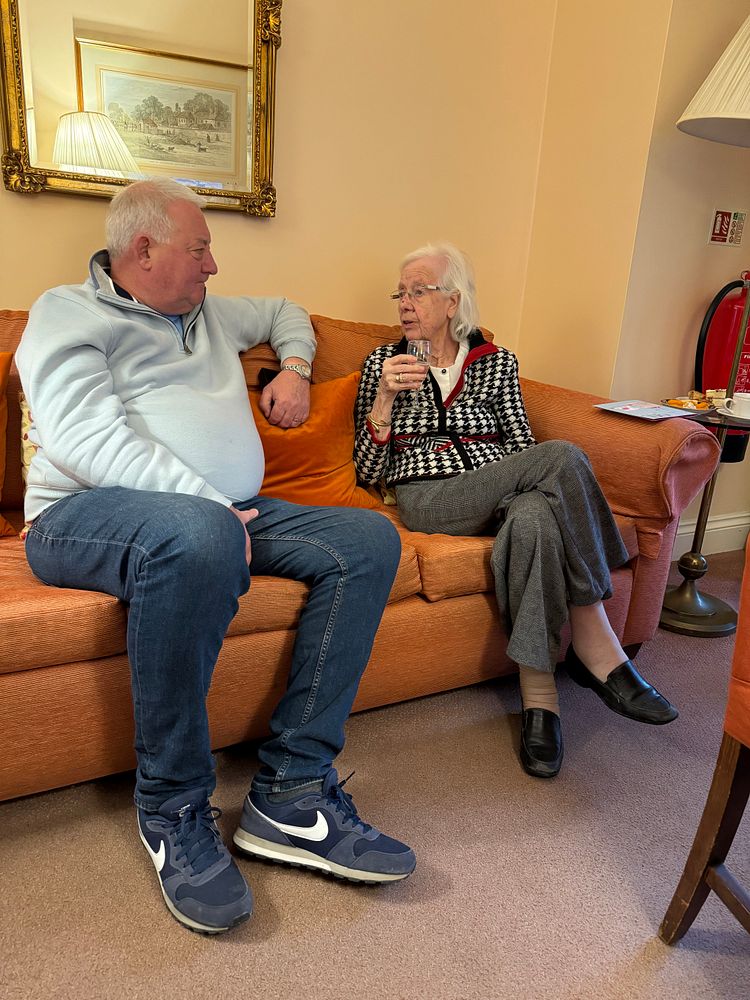 Clive and his mother Lilian talking on a sofa in a lounge